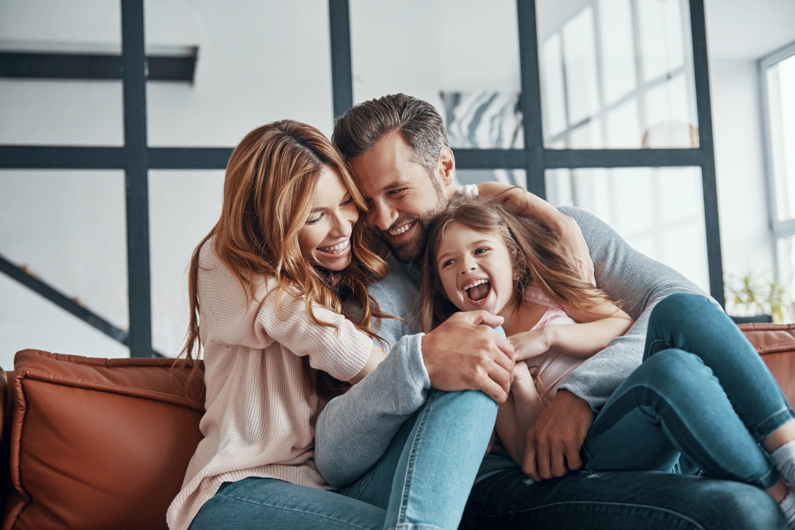 A family sitting on the couch hugging and smiling